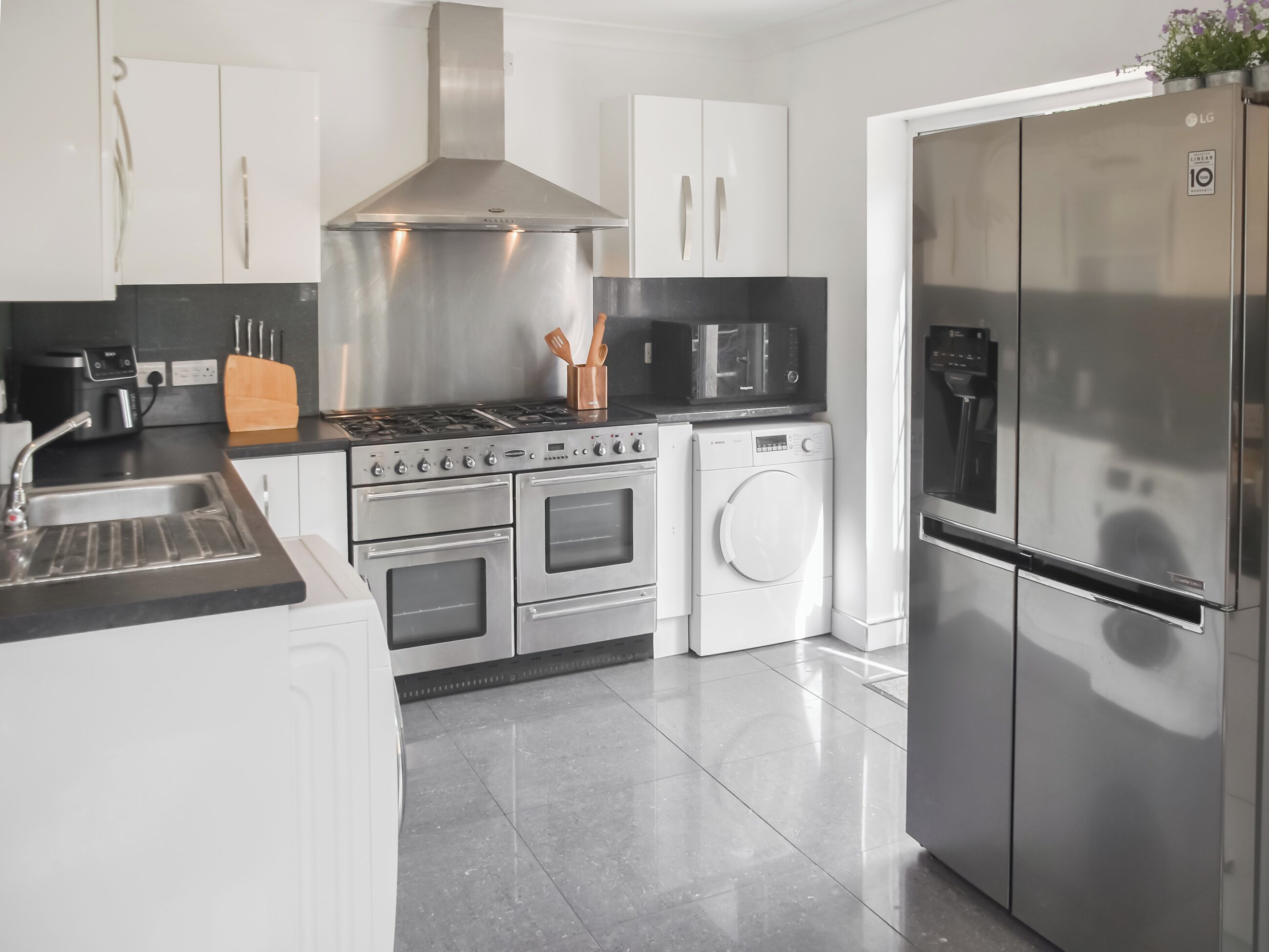 Une cuisine moderne équipée d’appareils électroménagers en acier inoxydable, notamment une cuisinière, un four, un four à micro-ondes et un réfrigérateur.