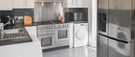Une cuisine moderne équipée d’appareils électroménagers en acier inoxydable, notamment une cuisinière, un four, un four à micro-ondes et un réfrigérateur.