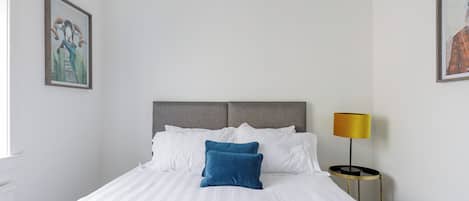 Een hotelkamer met een bed, een bedlampje en twee kunstwerken in lijsten aan de muur.