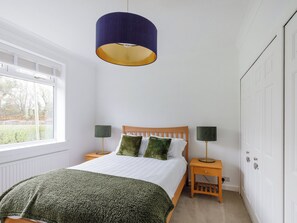 Ein Schlafzimmer mit einem Bett, zwei Nachttischen, einem Fenster und einem Kleiderschrank.