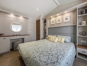 Um quarto com uma cama, uma penteadeira com espelho e estantes embutidas com objetos decorativos.