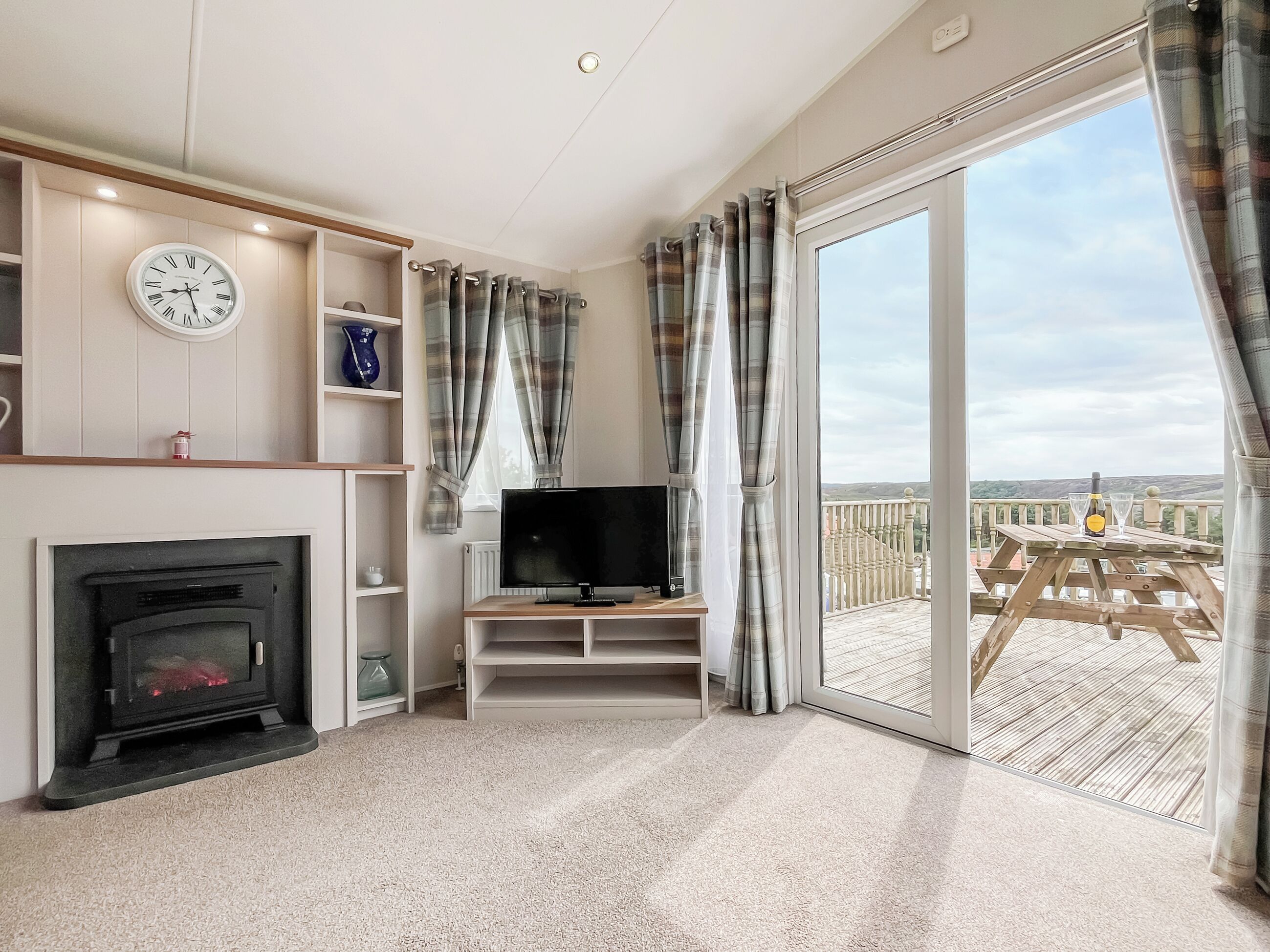 A living room with a fireplace, television, and a balcony with a view.