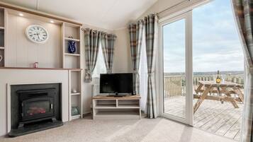 A living room with a fireplace, television, and a balcony with a view.