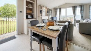 Un comedor moderno con una mesa de madera, sillas y vistas al exterior.