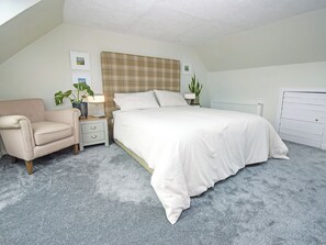 Ein Schlafzimmer mit einem Bett, einem Sessel, einem Nachttisch, einem Heizkörper und zwei Blumentöpfen.