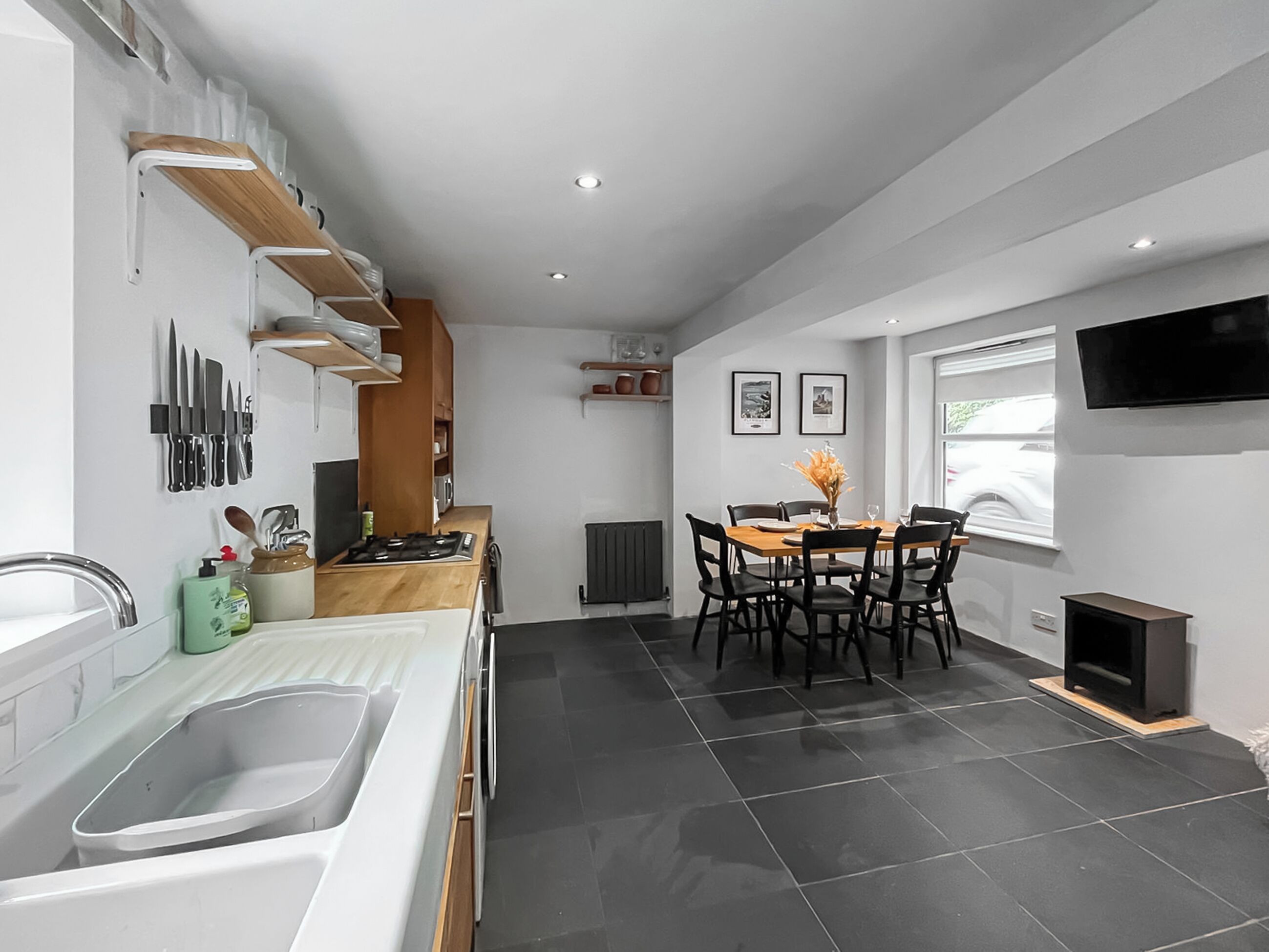 Una cocina moderna con comedor, estufa integrada y televisor montado en la pared.