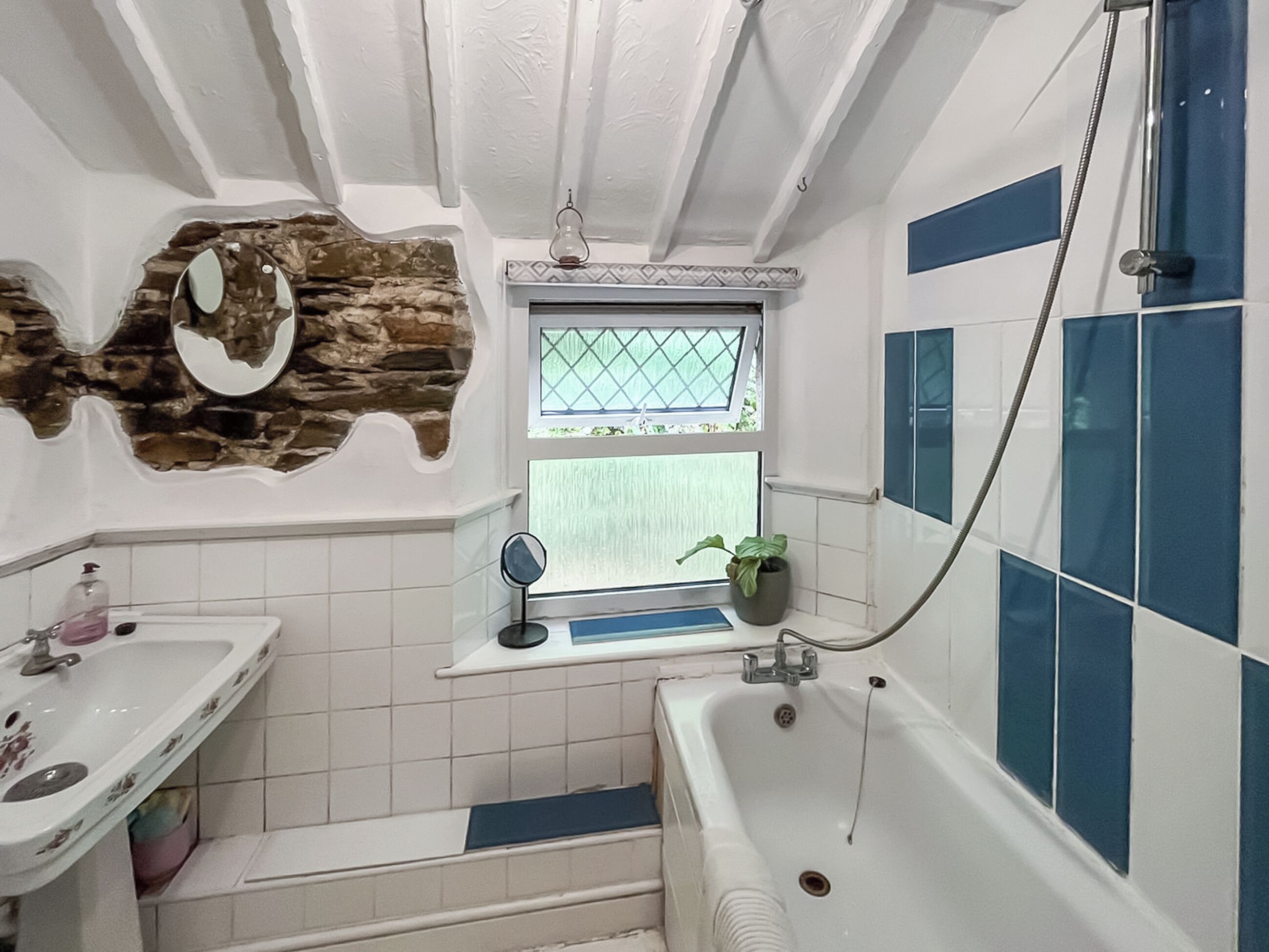 Un baño con lavamanos blanco, bañera, ducha y ventana con vistas.