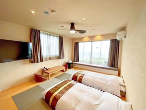 A hotel room with two beds, a TV, a desk, and a window with curtains. - LiVEMAX RESORT TSUKUBASAN (Tsukuba)