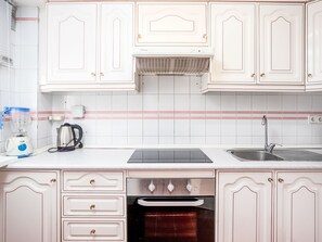 A kitchen with white cabinets, a built-in oven, a sink, and a coffee maker. - Los Arcos by Interhome (Torremolinos)