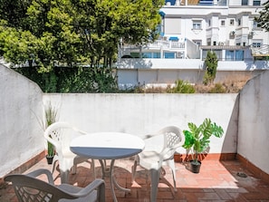 A small outdoor patio with a round table and two chairs, surrounded by potted plants. - Los Arcos by Interhome (Torremolinos)