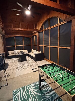 A room with a foosball table, a sofa set, and a large window with a view. - Modern 4BR, Patio, BBQ Grill and Theater— Perfect For (Grand Prairie)