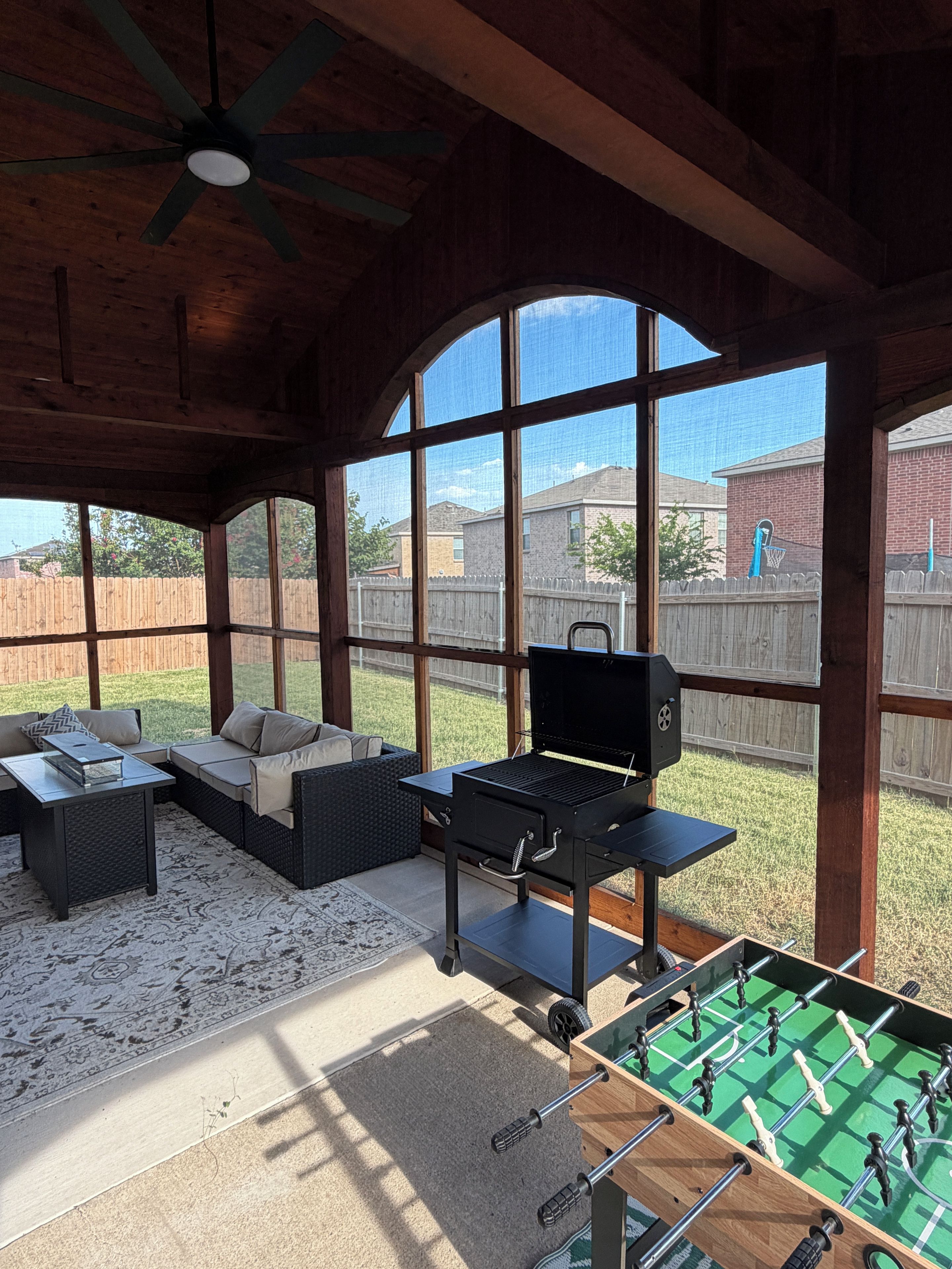 Une terrasse extérieure équipée d’un barbecue, d’un coin salon et d’une table de baby-foot.