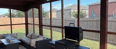 Un patio exterior con una parrilla, zona de estar y mesa de fútbol de mesa.