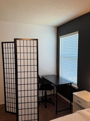 A room with a desk, chair, and a bed. - Modern 4BR, Patio, BBQ Grill and Theater— Perfect For (Grand Prairie)