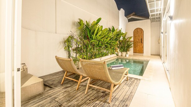 Ein Poolbereich mit Korbstühlen, einem kleinen Pool und Kübelpflanzen.