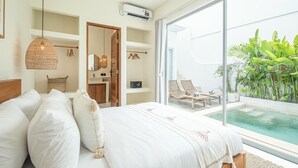 Ein Schlafzimmer mit einem großen Bett, einer Hängelampe und Blick auf einen Swimmingpool.