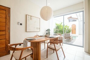 Un comedor con una mesa de madera, sillas y una lámpara colgante.