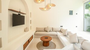 Ein modernes Wohnzimmer mit einer Couch, einem Couchtisch und einem an der Wand befestigten Flachbildfernseher.