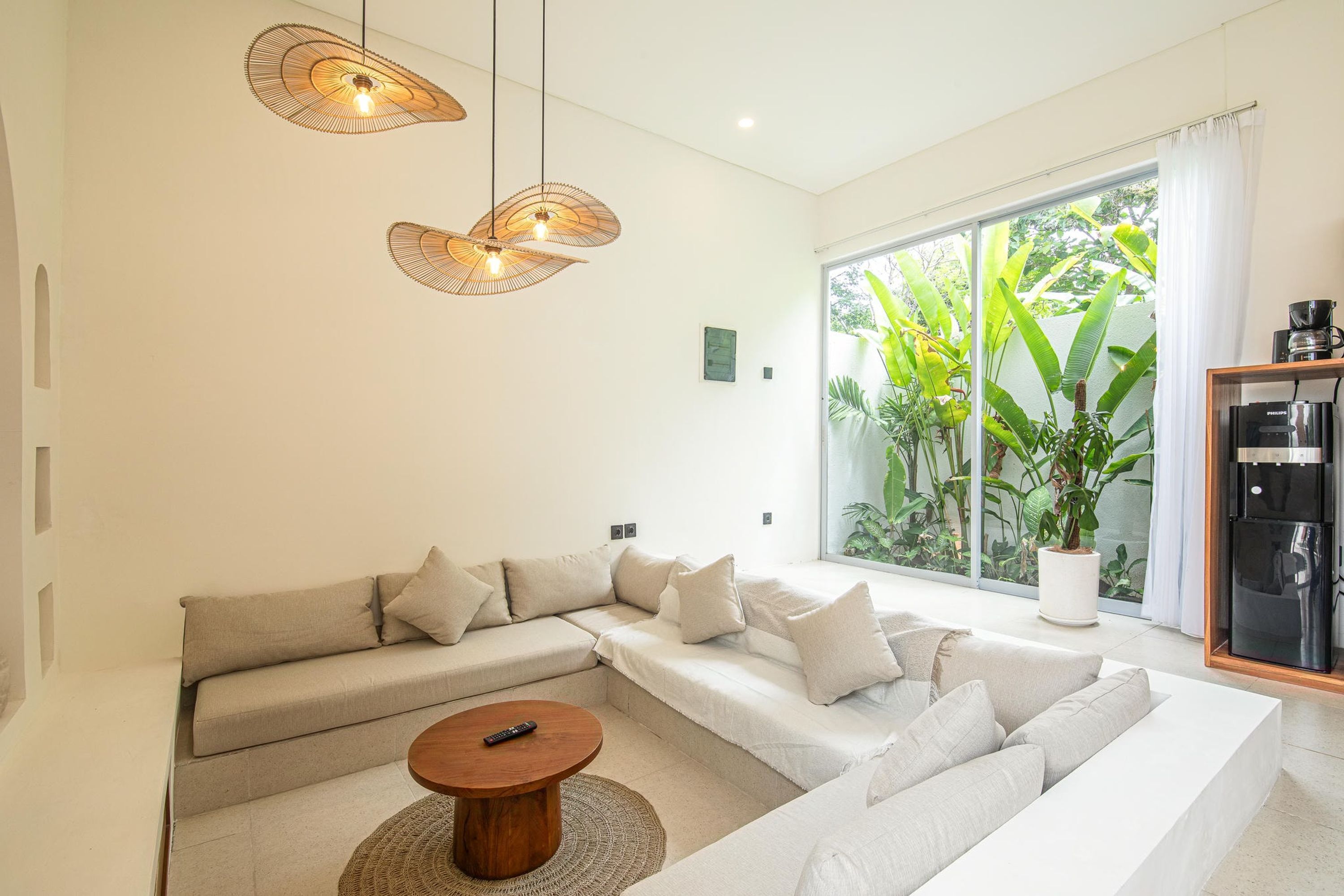 Uma sala de estar moderna com um sofá modular, uma mesa de centro e uma grande janela com vista para o verde.