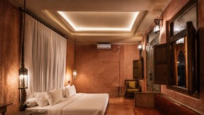 Ein Hotelzimmer mit einem großen Bett, einer Couch, einem kleinen Tisch und einem an der Wand befestigten Fernseher.