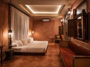 Ein Hotelzimmer mit einem großen Bett, einer Couch, einem kleinen Tisch und einem an der Wand befestigten Fernseher.
