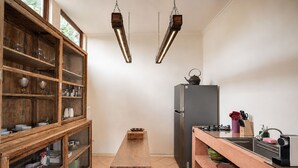 Eine Küche mit Holzschränken, einem zentralen Tisch, einem Kühlschrank und einer Spüle.