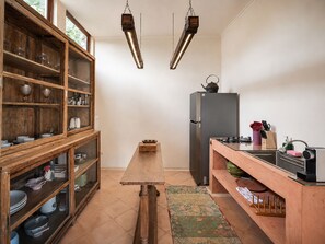 Eine Küche mit Holzschränken, einem zentralen Tisch, einem Kühlschrank und einer Spüle.