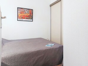 Une pièce avec un lit, une porte et un tableau accroché au mur.