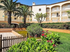 A courtyard with a pool, palm trees, and a wooden fence. - L'Annonciade by Interhome (Port Cogolin)