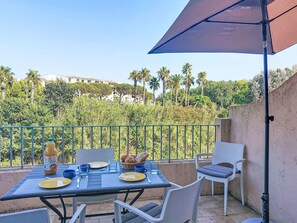 An outdoor dining area with a table set for two, chairs, and a table umbrella. - L'Annonciade by Interhome (Port Cogolin)