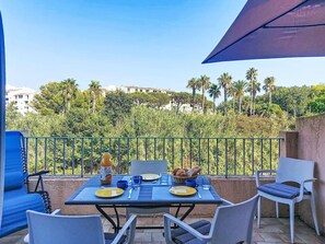 A table set outdoors with chairs, a bottle, plates, and glasses, overlooking a residential area with palm trees. - L'Annonciade by Interhome (Port Cogolin)