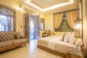 A bedroom with a bed, a sofa, a glass side table, and a view of the outdoors. - Stylish Villa Uluwatu Enclosed Living AC (Pecatu)