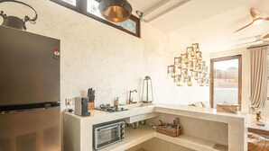 Eine kleine Küche mit integriertem Kühlschrank, einem Gasherd, einem Toaster und einer Pendelleuchte.