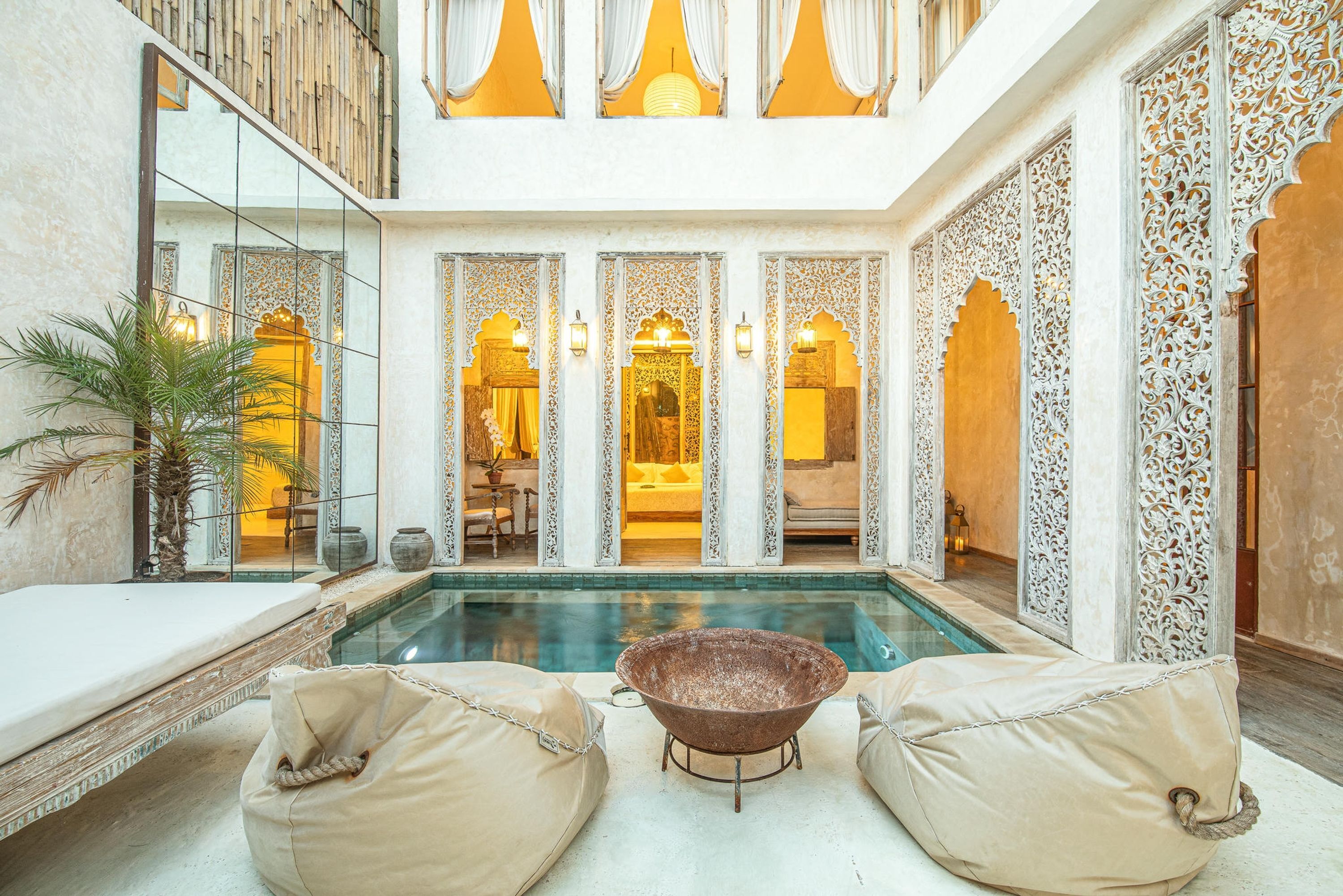 A pool area with a hot tub, lounge chairs, and a view of a room with traditional decor.