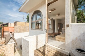 Um imóvel residencial com área externa coberta, deck de madeira e vista do interior, incluindo sala de estar e área de jantar.