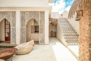 A traditional courtyard with intricate archways, a patterned staircase, and a simple seating area. - Stylish Villa Uluwatu Enclosed Living AC (Pecatu)
