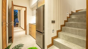 Une cuisine moderne dotée d’un réfrigérateur en acier inoxydable, de meubles en bois et d’un four encastré.