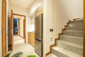 Eine moderne Küche mit einem Edelstahl-Kühlschrank, Holzschränken und einem eingebauten Backofen.