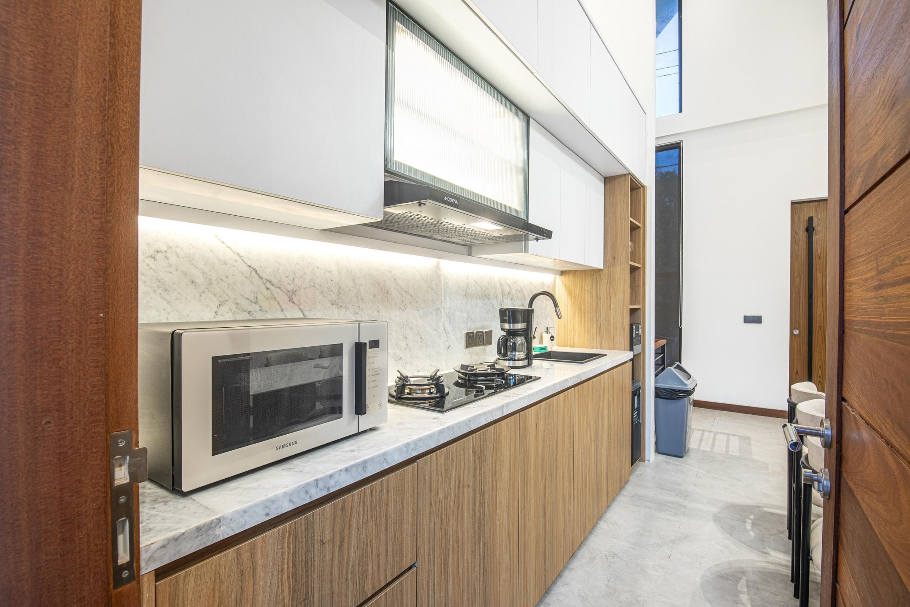 Une cuisine moderne dotée d’appareils électroménagers en acier inoxydable, de meubles en bois et d’un plan de travail en marbre.