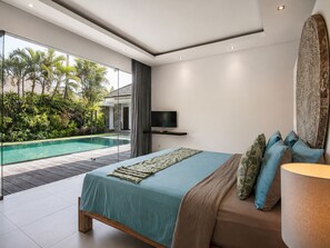 Ein modernes Schlafzimmer mit einem großen Bett, einem Fernseher und Blick auf einen Swimmingpool.
