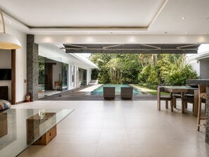 Ein zeitgemäßer Außenbereich mit Pool, Sitzgelegenheiten und einem Glastisch.