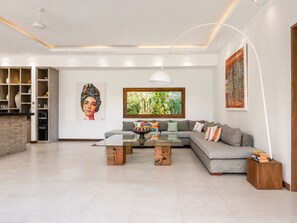 Ein modernes Wohnzimmer mit einem Ecksofa, einem Couchtisch und einem großen Fenster.