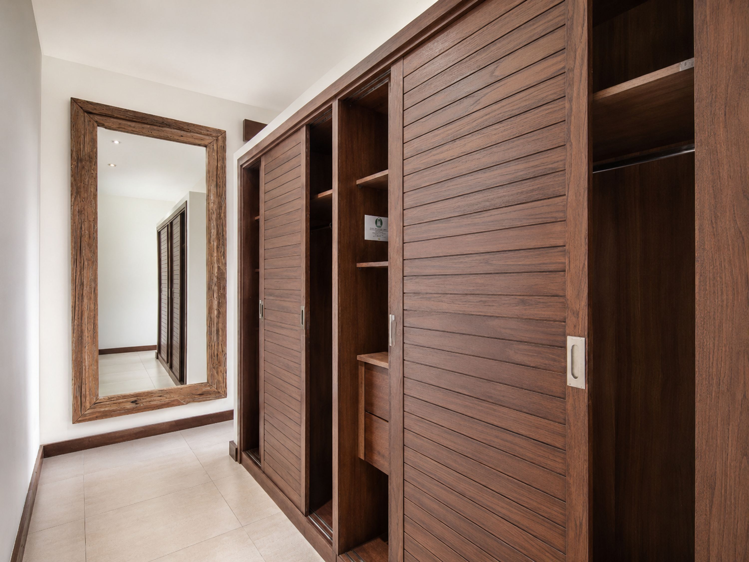 Un couloir avec une armoire en bois et un miroir.