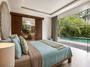 A bedroom with a large bed, a view of a swimming pool, and a sliding door leading to a bathroom. - Splendid Villa 3Br Center Seminyak (Keroboken Kelod)