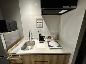 A compact kitchenette with a sink, a coffee maker, and a scale on the countertop.