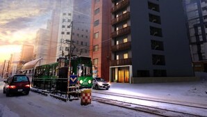 A tram on a snowy street with modern buildings in the background.