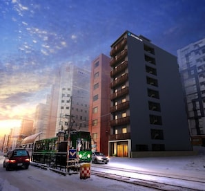 A tram on a snowy street with modern buildings in the background.