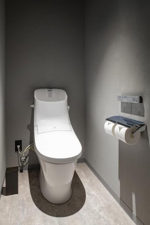 A modern toilet with a wall-mounted paper towel dispenser and a flush handle. - ALPHABED INN Sapporo Odori Koen (Sapporo-shi)
