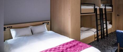 A hotel room with a single bed, a bunk bed, a desk, and a chair.