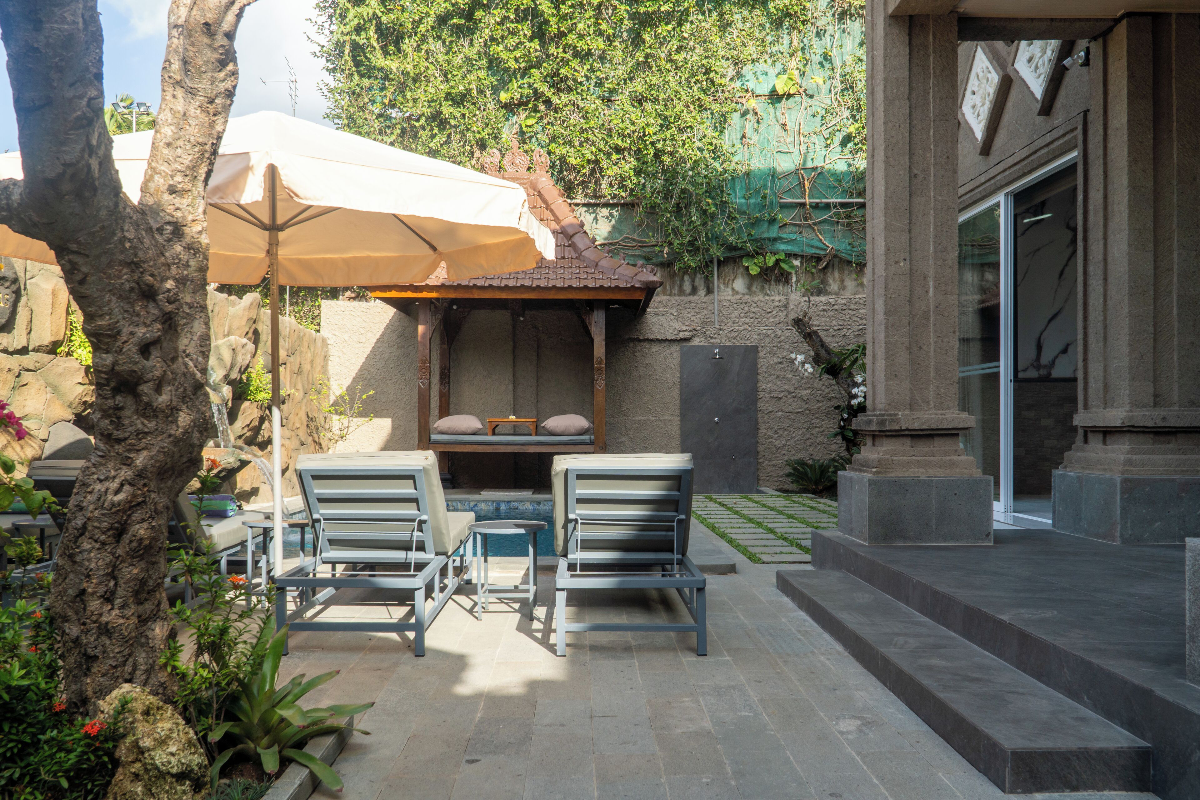 Un espace patio aménagé avec des sièges, une petite table et un élément décoratif aquatique.